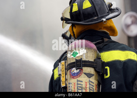 Two fire fighters surrounded by smoke while putting out a fire with a hose line Stock Photo
