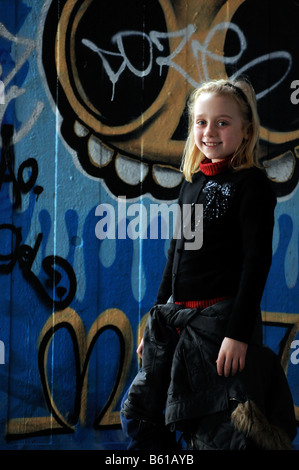 Royalty free photograph of young girl posing for photograph next to graffiti on wall in London UK Stock Photo
