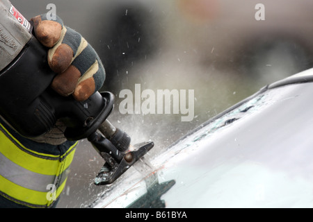 A firefighter cutting the glass windshield of a car during extrication Stock Photo