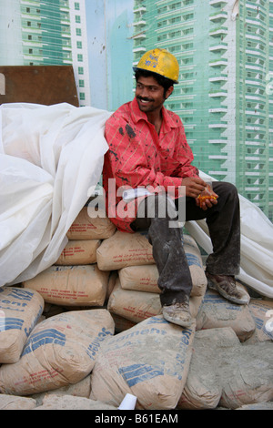 construction worker wearing hard hat sitting on cement bags on construction building site dubai uae Stock Photo