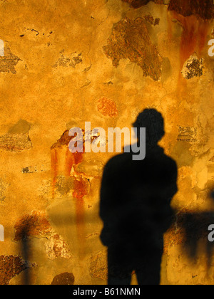 A mans shadow cast against a stone wall at dawn Stock Photo