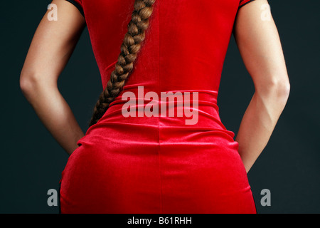 Woman wearing a red velvet dress and pony tail from behind, partial view Stock Photo