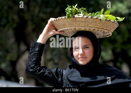 Young woman wearing traditional costume carrying a basket on her head at Cavalcata Sarda Festival in Sassari, Sardinia, Italy, Stock Photo