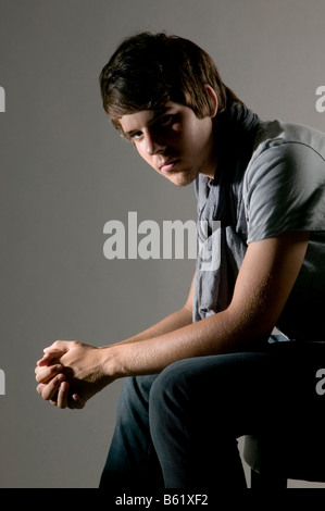 Young man sitting on a chair, lost in thought Stock Photo