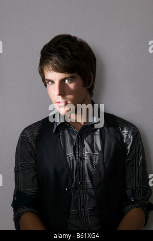 Young man sitting confidently in front of a wall Stock Photo