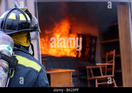 A fire fighter ready to fight a fire in a container full of furniture Stock Photo