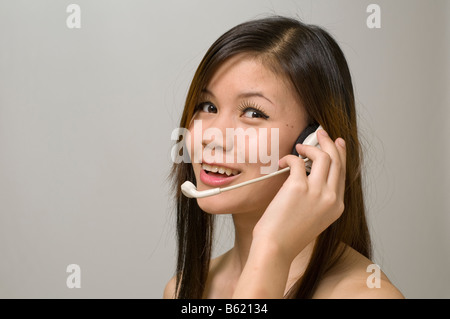 Attractive Asian business woman wearing headset and smiling Stock Photo