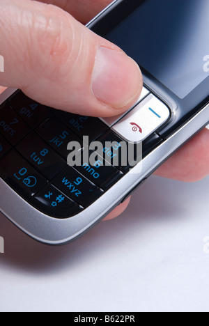Cell or mobile phone held in hand with thumb operating it. Shallow focus on action keys Stock Photo