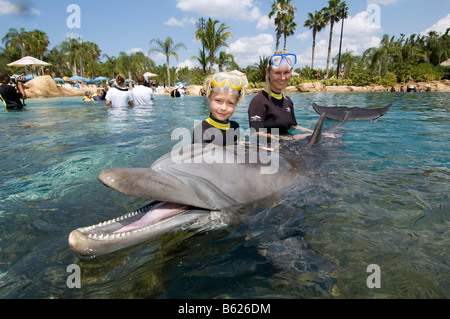 Mother and child playing with a Dolphin (Tursiops truncatus), Discovery Cove, Orlando, Florida, USA, North America Stock Photo