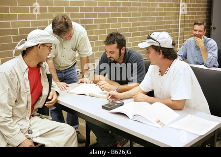 An adult education teacher and students solving a problem together Stock Photo