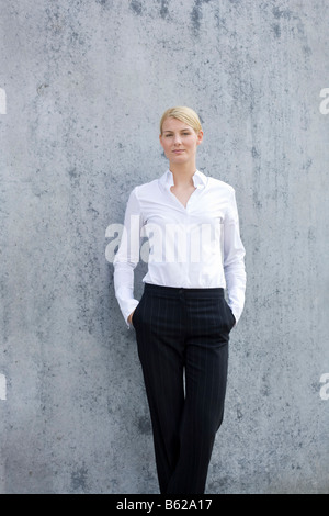 Young blonde woman wearing business clothes standing in front of a grey wall Stock Photo
