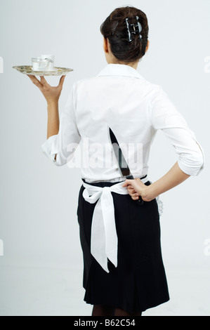Young woman dressed as a waitress hiding a knife behind her back Stock Photo