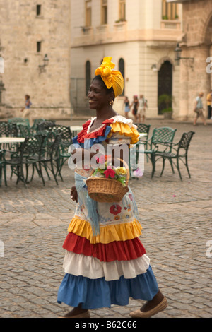 Cuban woman in traditional dress carrying a basket with flowers, havana, cuba Stock Photo