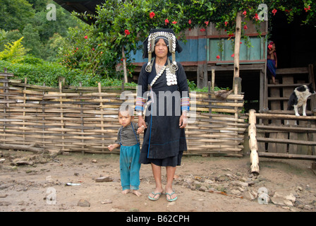 Mother of the Akha Phixo tribe dressed in traditional costume holding a child by the hand, Ban Phapoun Mai, Phongsali Province, Stock Photo