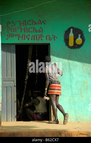 Young man wearing a mini skirt at the entrance of a bar to get Tedj, honey beer, Keyafer, Ethiopia, Africa Stock Photo