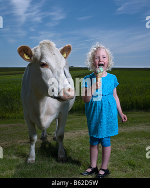 Young girl eating an Ice cream cone with white dairy cow, Eastern Iceland Stock Photo