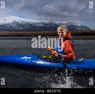 Teenage boy kayaking in river with Oraefajokull glacier in background, Eastern Iceland Stock Photo