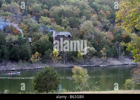 Rustic Log cabins in the fall foliage of the hills of Missouri with a canoe in the lake below Stock Photo