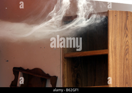 The smoke wafting out of a container full of furniture There is ash debris in the air Stock Photo