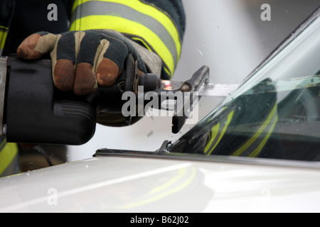 A firefighter cutting the glass windshield of a car during extrication Stock Photo