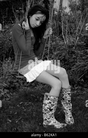 Teenage girl sitting on a swing looking unhappy