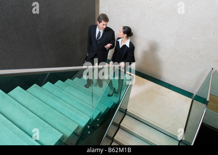 Businessman and a businesswoman moving up stairs Stock Photo