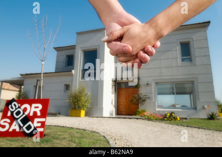 Close-up of a couple's hands with house in the background Stock Photo
