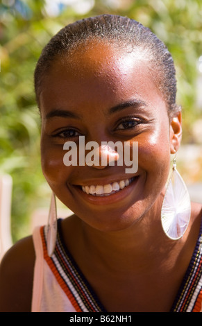 Beautiful portrait of young woman from Haiti in dress and earrings outdoors with smile Stock Photo
