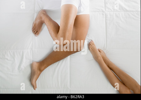 Low section view of a man and a woman lying on the bed Stock Photo