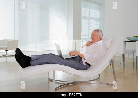 Side profile of a senior man using a laptop and smiling Stock Photo