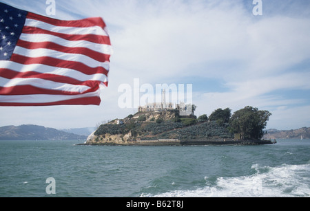 Alcatraz Island and prison, San Francisco Bay, seen from boat departing the island, with Stars and Stripes Stock Photo