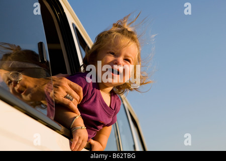 Close-up of a baby girl looking out of a car window and smiling Stock Photo