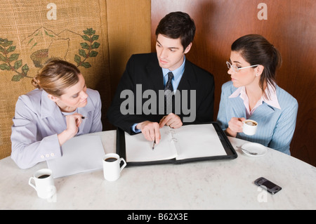 Two businesswomen and a businessman discussing in a cafe Stock Photo