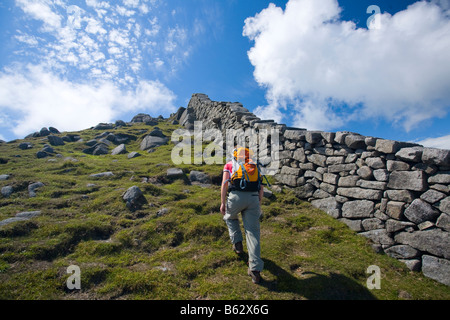 Walker beside the Mourne Wall on the ascent of Slieve Bearnagh, Mourne Mountains, County Down, Northern Ireland, UK. Stock Photo