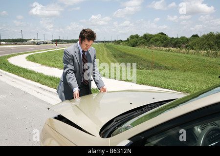 A businessman with car trouble checking under the hood Stock Photo