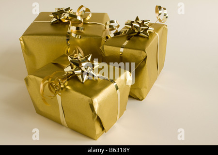 A group of three parcels gift wrapped in gold paper Stock Photo