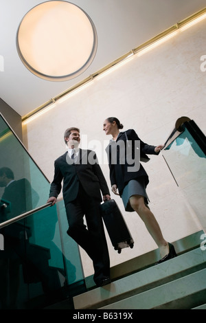 Low angle view of a businessman with a businesswoman moving down staircase Stock Photo