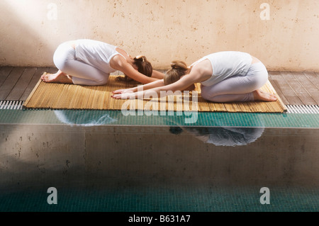 Side profile of two young women exercising at the poolside Stock Photo