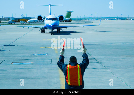 Rear view of a ground crew directing an airplane Stock Photo