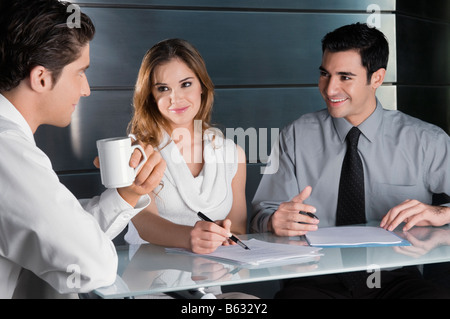 Two businessmen and a businesswoman talking in an office Stock Photo