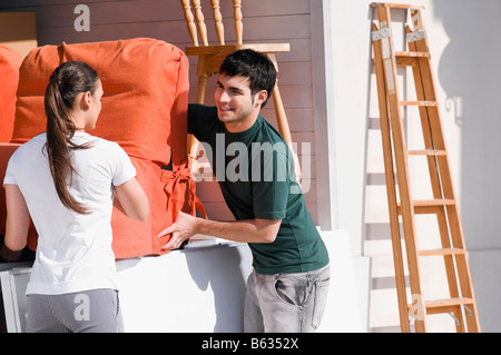 Young couple carrying an armchair Stock Photo