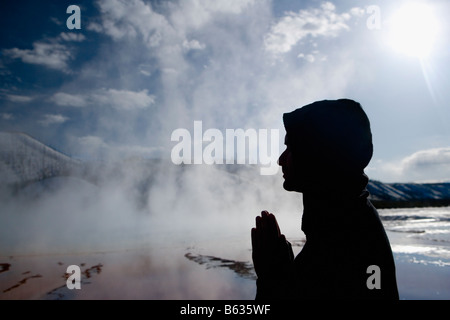 Silhouette of a man in a prayer position near a hot spring, Grand Prismatic Spring, Yellowstone National Park, Wyoming, USA Stock Photo