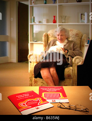 Elderly woman trying to keep warm at home Stock Photo