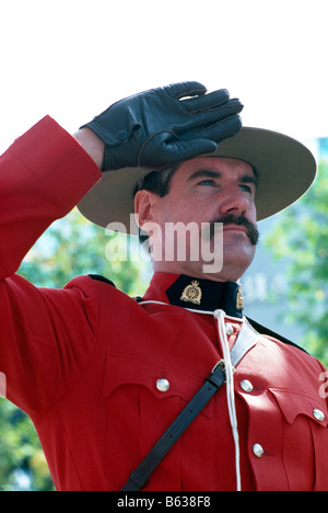 A Canadian Mountie (RCMP) Royal Canadian Mounted Police Officer saluting and wearing Traditional Red Surge Uniform Stock Photo