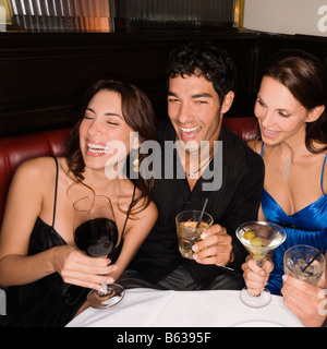 Three friends sitting at a table and smiling Stock Photo
