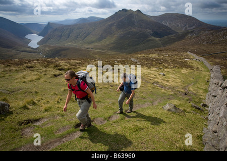 Walkers above the Silent Valley near the summit of Slievenaglogh, Mourne Mountains, County Down, Northern Ireland, UK. Stock Photo