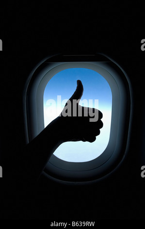 Close-up of a person's hand showing thumbs up sign in an airplane Stock Photo