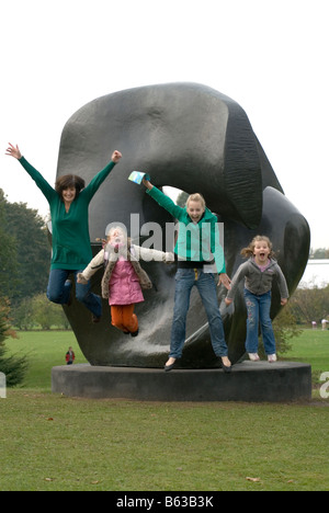 Family jump from with Henry Moore's Locking Piece sculpture at Kew gardens in 2007. Stock Photo