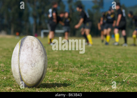 Close-up of a rugby ball in a field with rugby players in the background Stock Photo