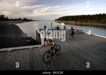 4 four children riding bikes on the wharf at Mapua Nelson New Zealand Stock Photo